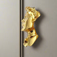 Gold-colored pendant with a face design on a white background