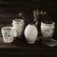 Set of rustic ceramic pots with dried flowers on a wooden surface
