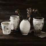 Set of rustic ceramic pots with dried flowers on a wooden surface