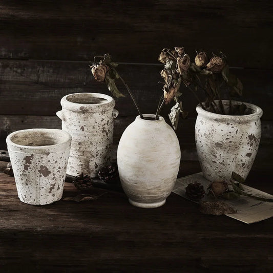 Set of rustic ceramic pots with dried flowers on a wooden surface