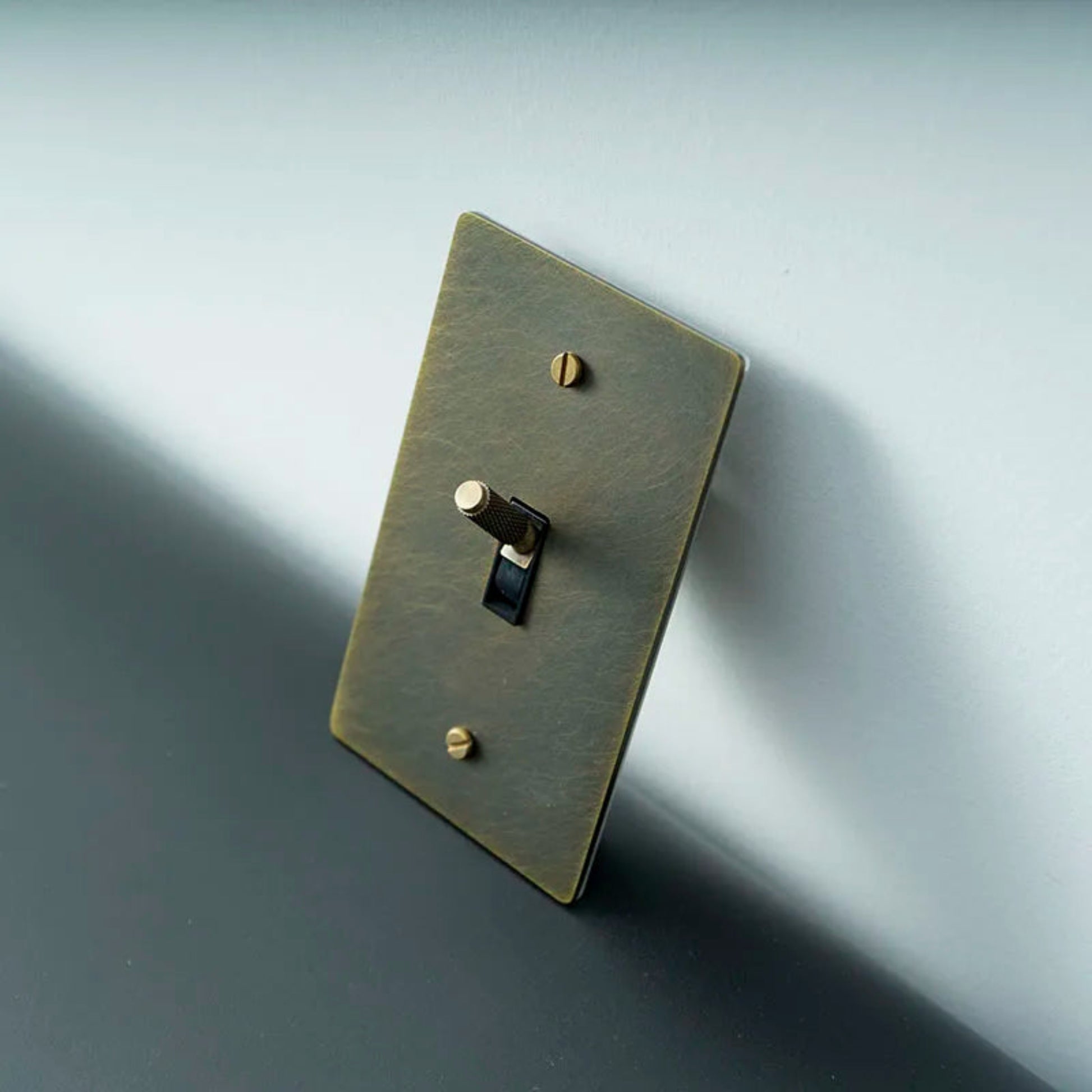 Bronze light switch plate with a single toggle on a gradient gray background