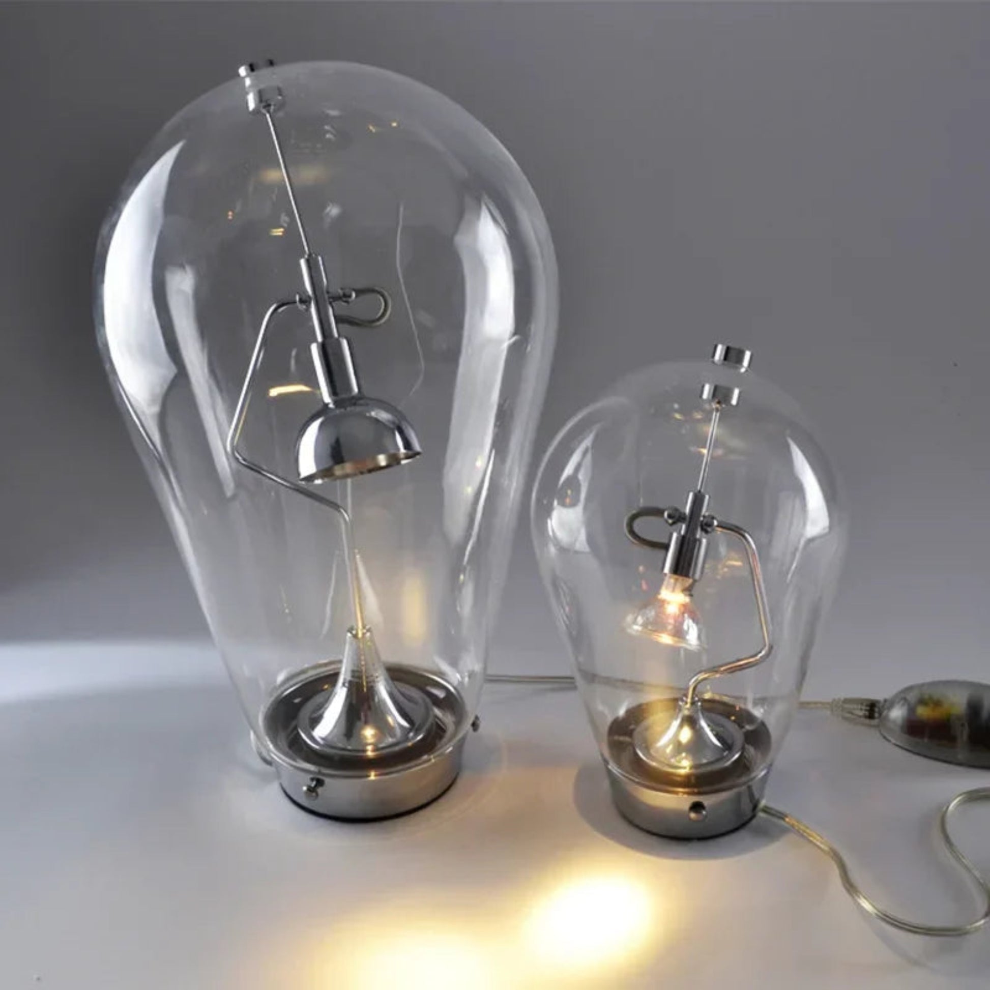 Two glass bulb lamps with metallic bases on a white surface.