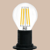 Clear light bulb with yellow filaments inside a black base on a white background