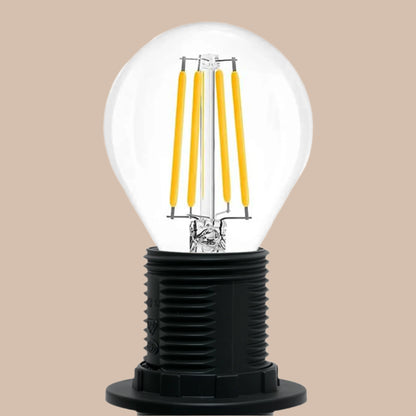Clear light bulb with yellow filaments inside a black base on a white background