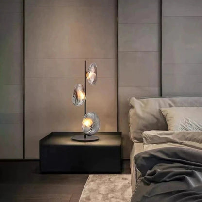 Modern bedroom with a stylish lamp on a nightstand and a bed in the background.