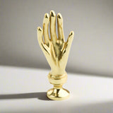 Gold hand-shaped cabinet handle on a white background