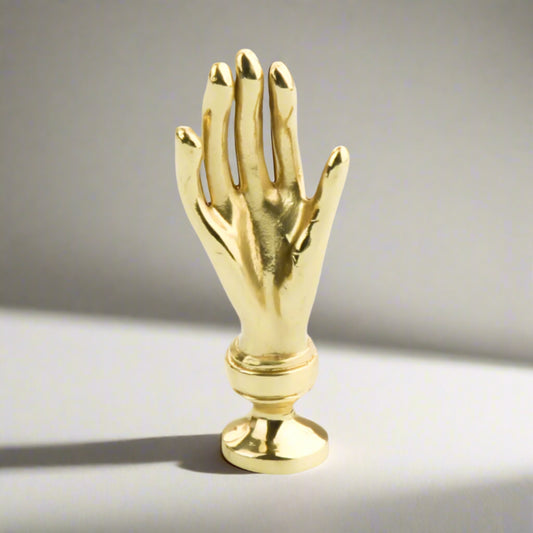 Gold hand-shaped cabinet handle on a white background