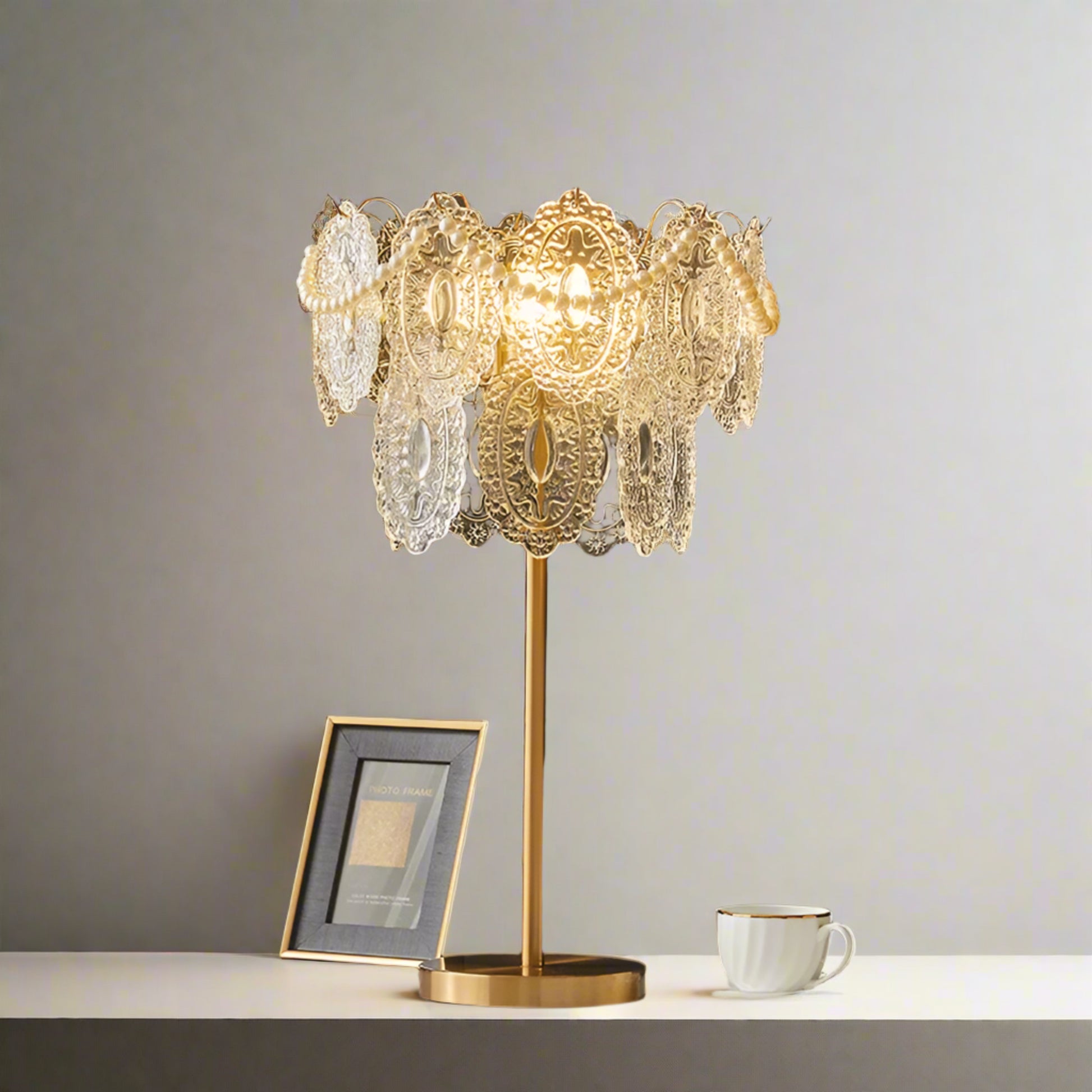 Decorative table lamp with intricate design on a stand, placed on a surface with a dark wall background.