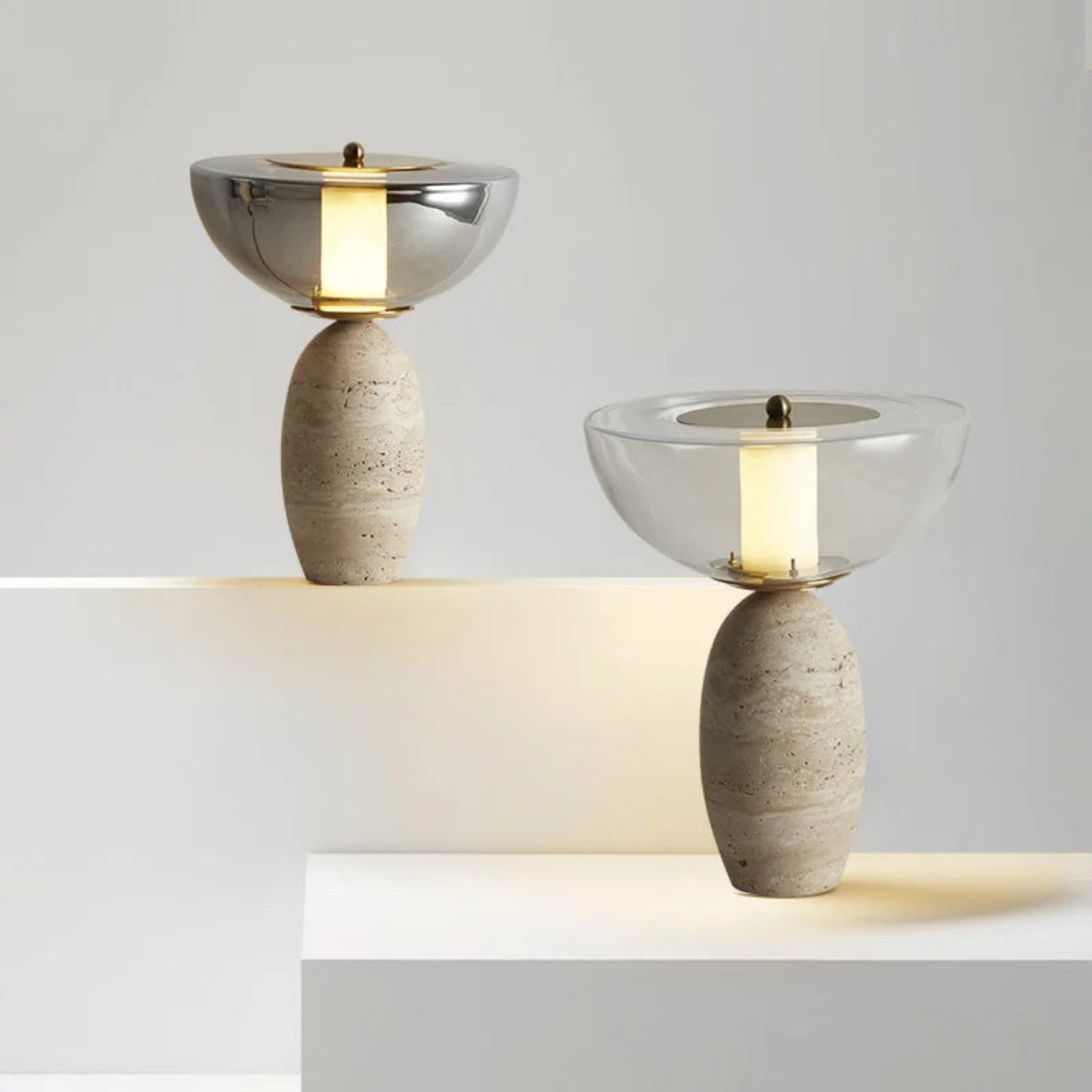 Two table lamps with stone bases and glass shades on a white surface.