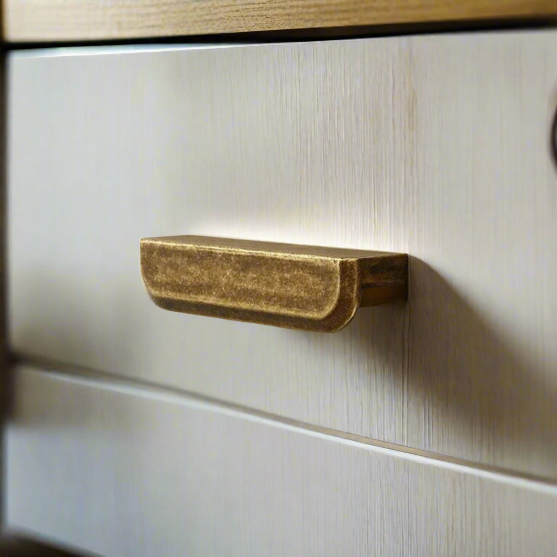 Close-up of a brass drawer handle on a wooden cabinet.