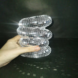 Hand holding a silver, spiral-patterned object against a dark background