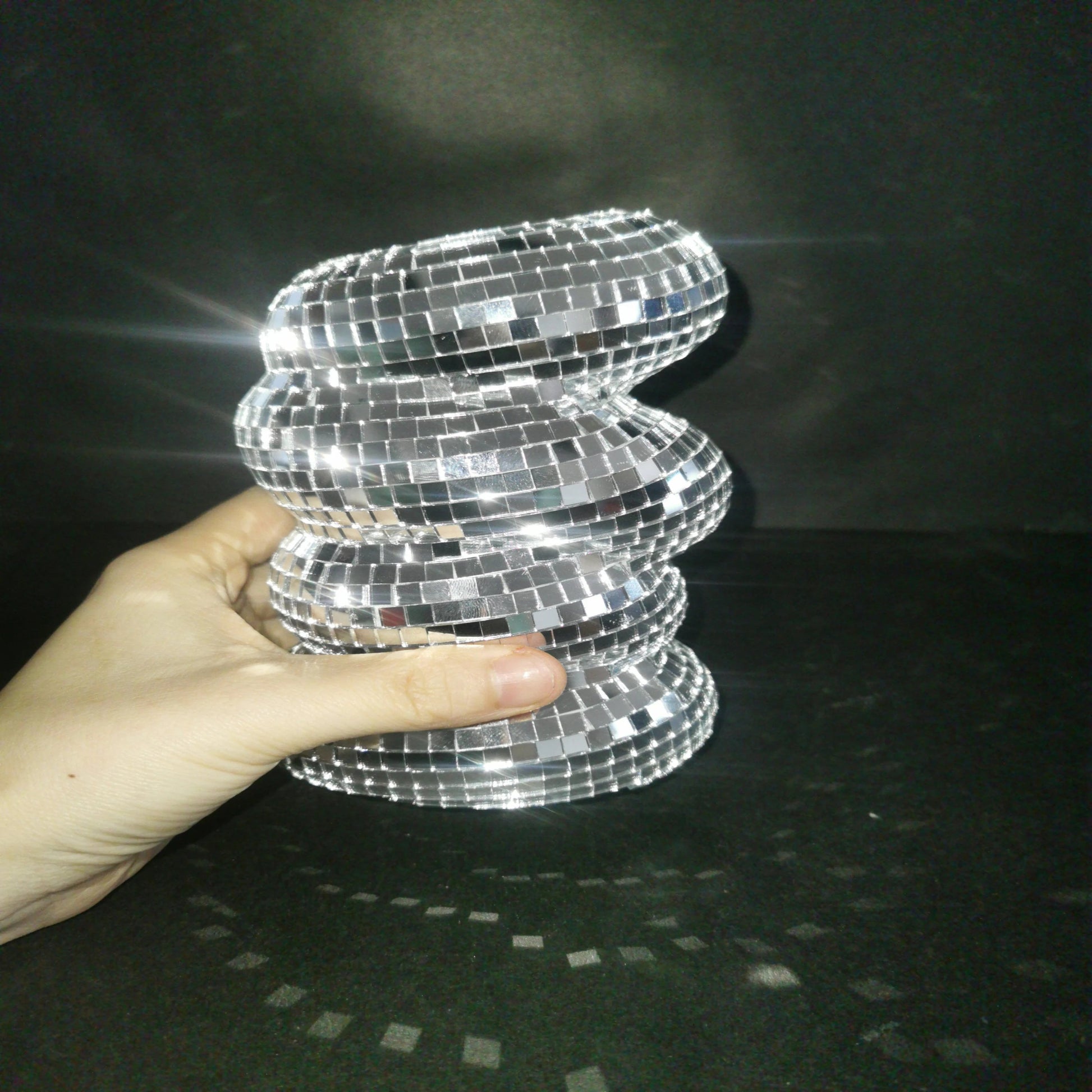 Hand holding a silver, spiral-patterned object against a dark background