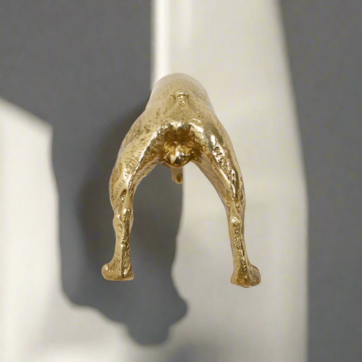 Gold metallic sculpture of a figure on a white background