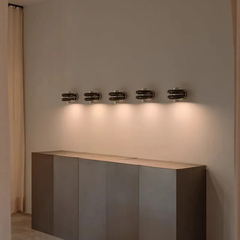 Modern wall-mounted light fixture on a neutral wall with a console table below.
