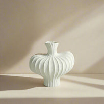 White textured vase on a light surface with a gray paneled wall background