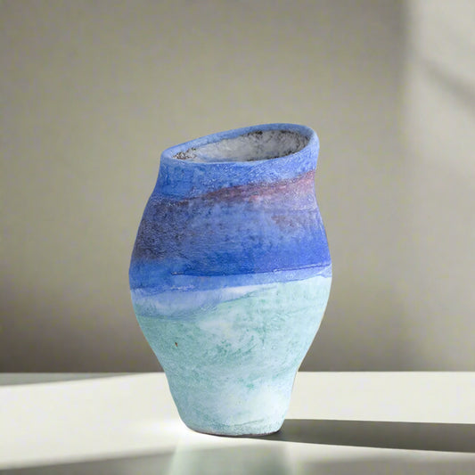 Ceramic vase with gradient blue and green colors on a light gray background