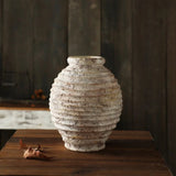 Textured ceramic vase on a wooden surface with a dark background