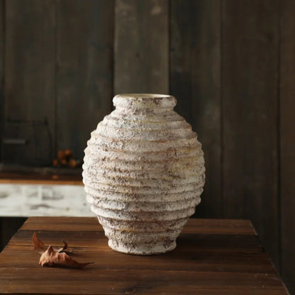 Textured ceramic vase on a wooden surface with a dark background