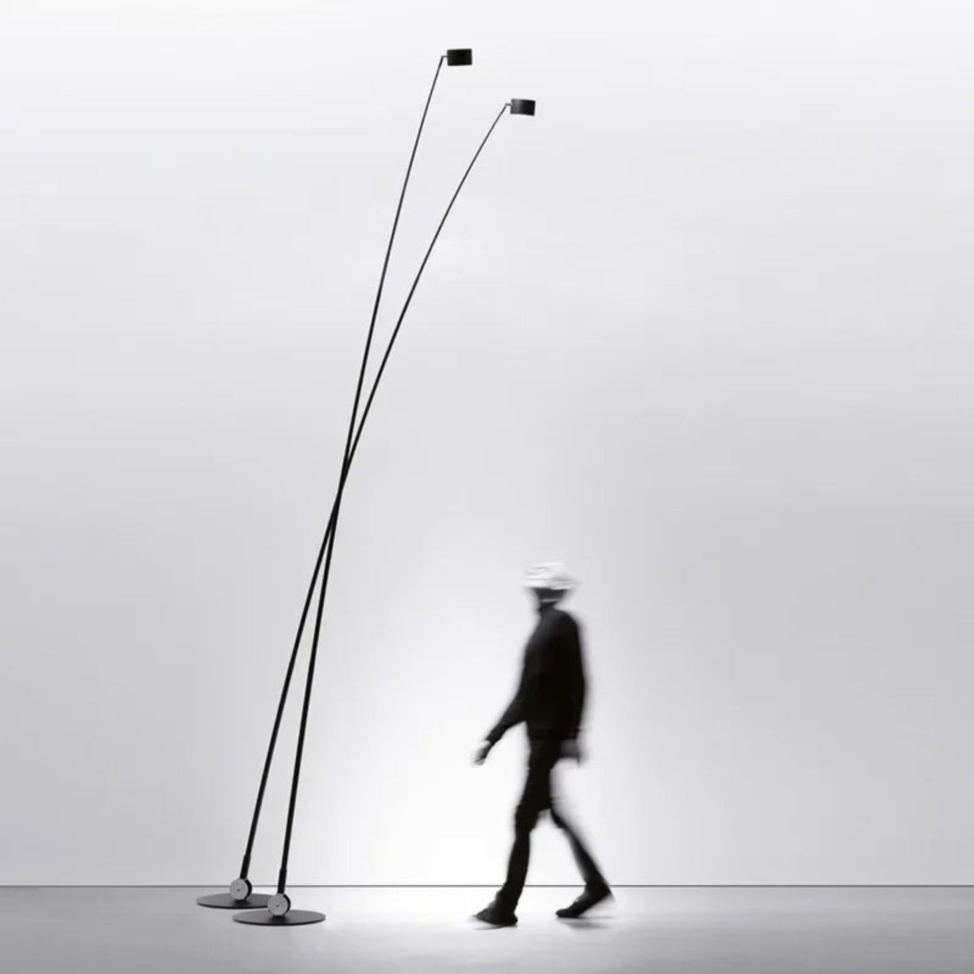 Modern floor lamp with two long poles on a plain background