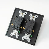 Two electrical outlets on a black faceplate with white and gold screws against a white background.