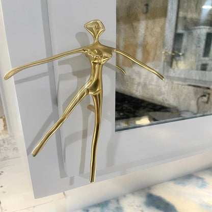 Gold abstract sculpture on a white surface with a mirror in the background