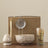 Set of ceramic and metal items including a bowl, strainer, and container with a wooden stick on a beige background.