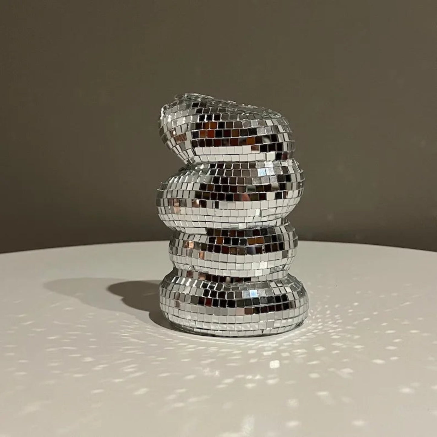 Decorative object made of reflective mosaic tiles on a neutral background
