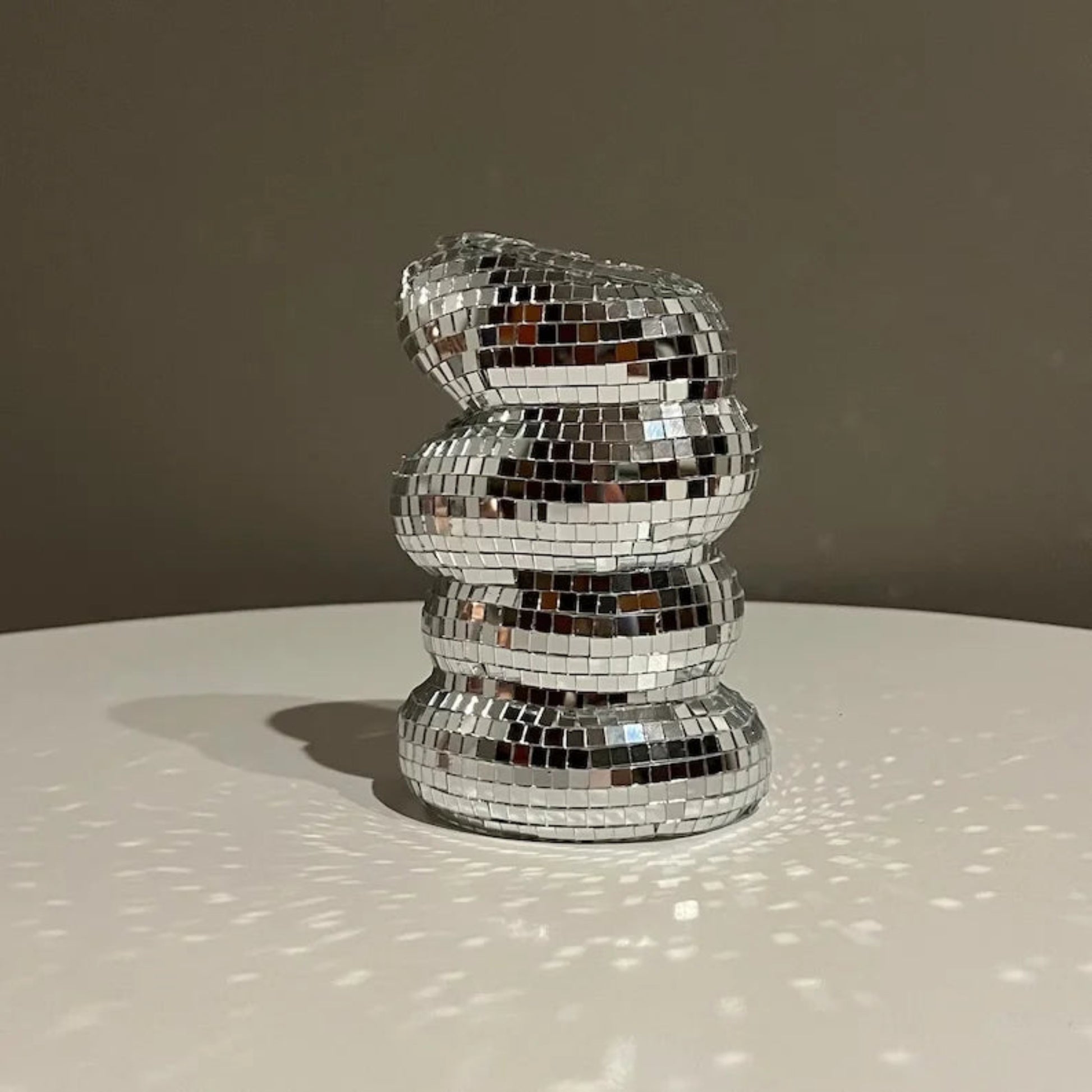 Decorative object made of reflective mosaic tiles on a neutral background