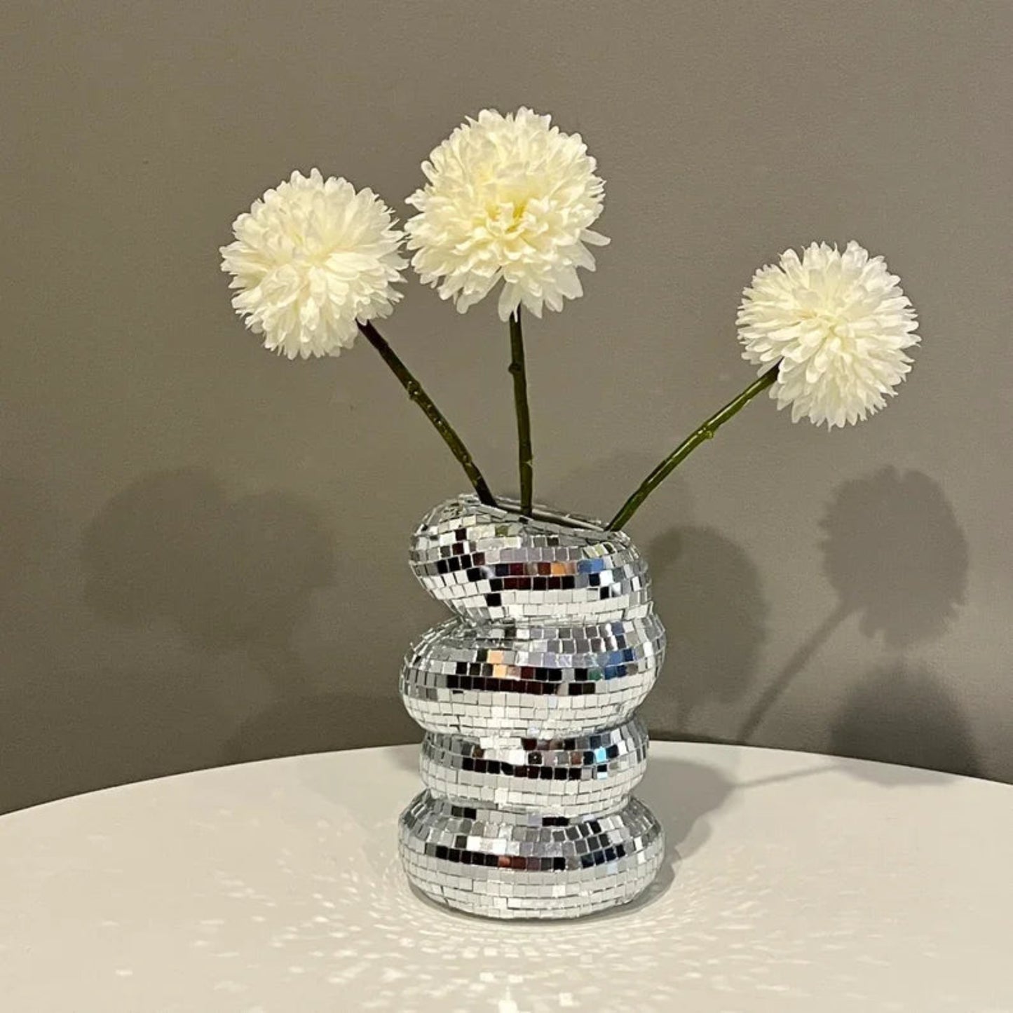 Silver mosaic vase with white flowers on a neutral background