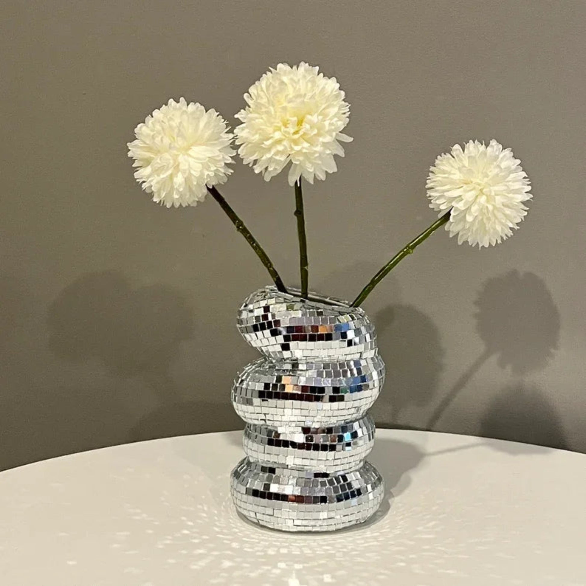 Silver mosaic vase with white flowers on a neutral background