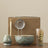 Tea-making set with ceramic bowl, strainer, and glass on a beige background