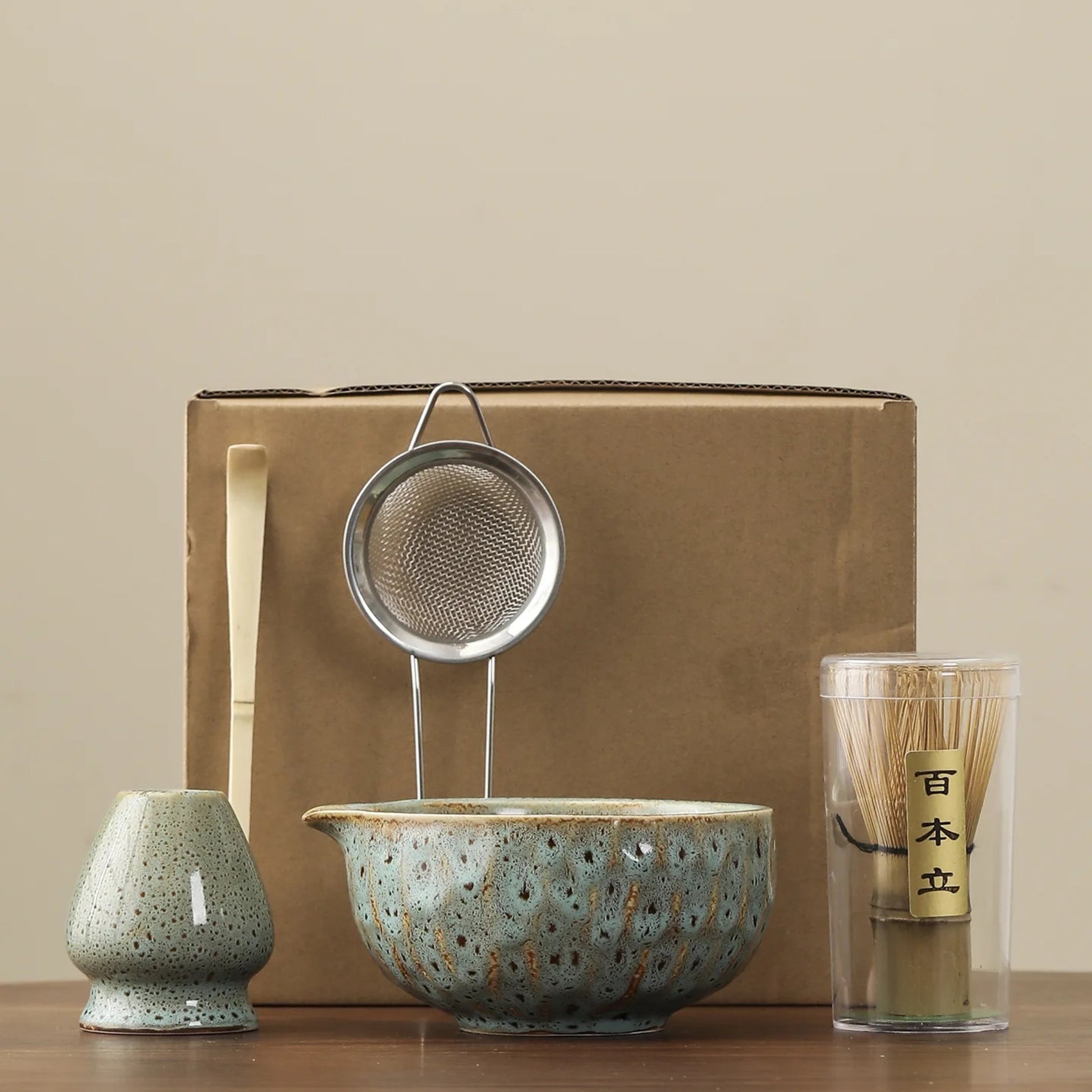Tea-making set with ceramic bowl, strainer, and glass on a beige background