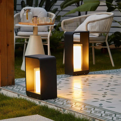 Two outdoor lamps on a patio with chairs and a small table in the background.