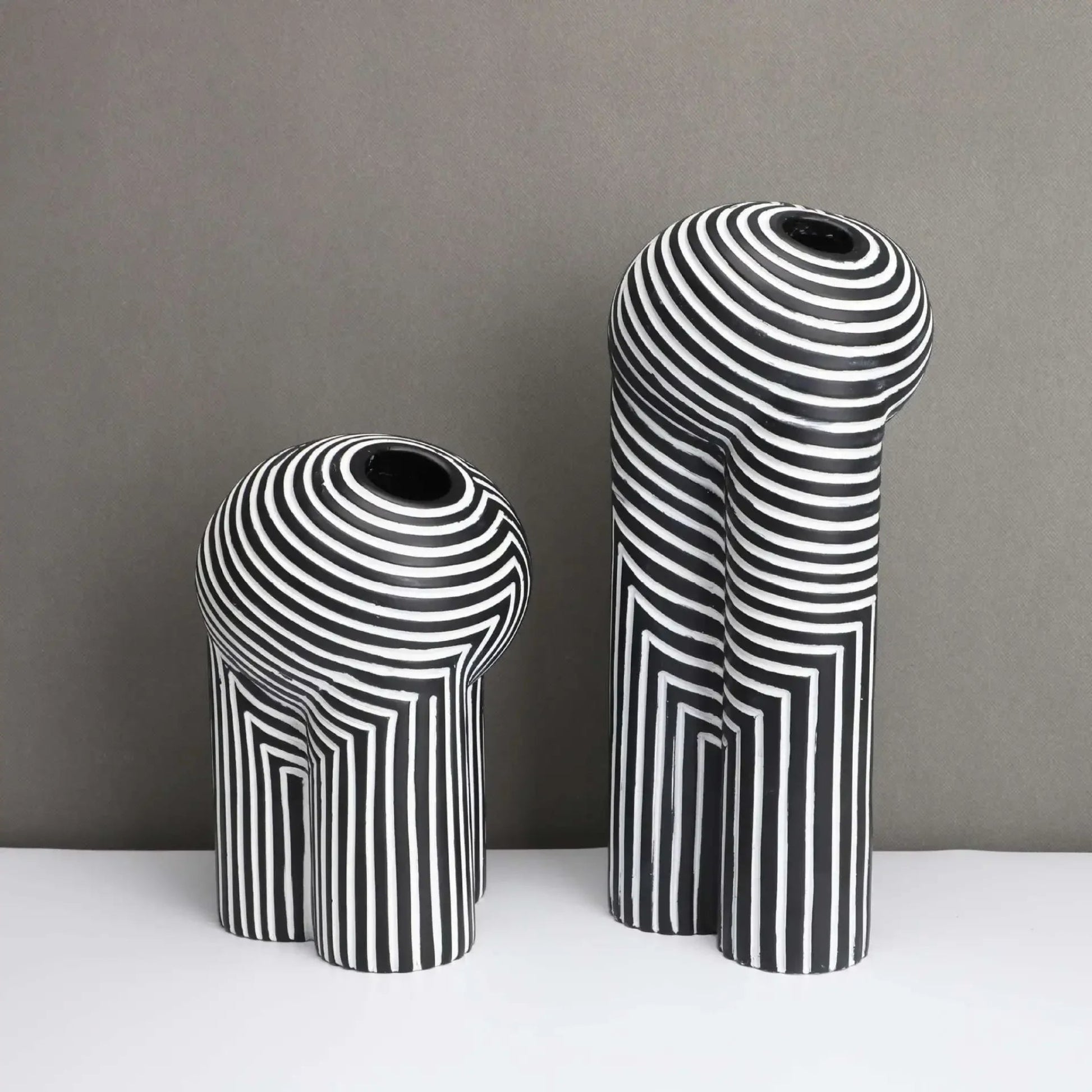 Two black and white striped vases on a gray background