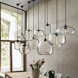 Modern pendant lights with glass shades in a room with a window and table.