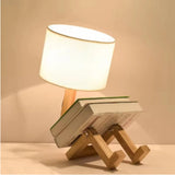 Small wooden lamp with a white shade on top of books against a beige background