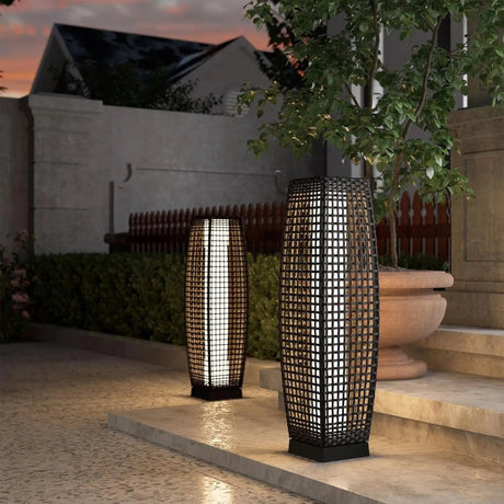 Two outdoor lamps on a patio with a building and tree in the background