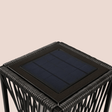 Black woven side table with a solar panel on a beige background