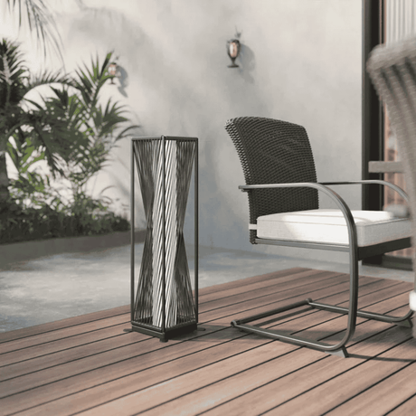 Decorative outdoor lamp on a wooden deck with a chair and plants in the background