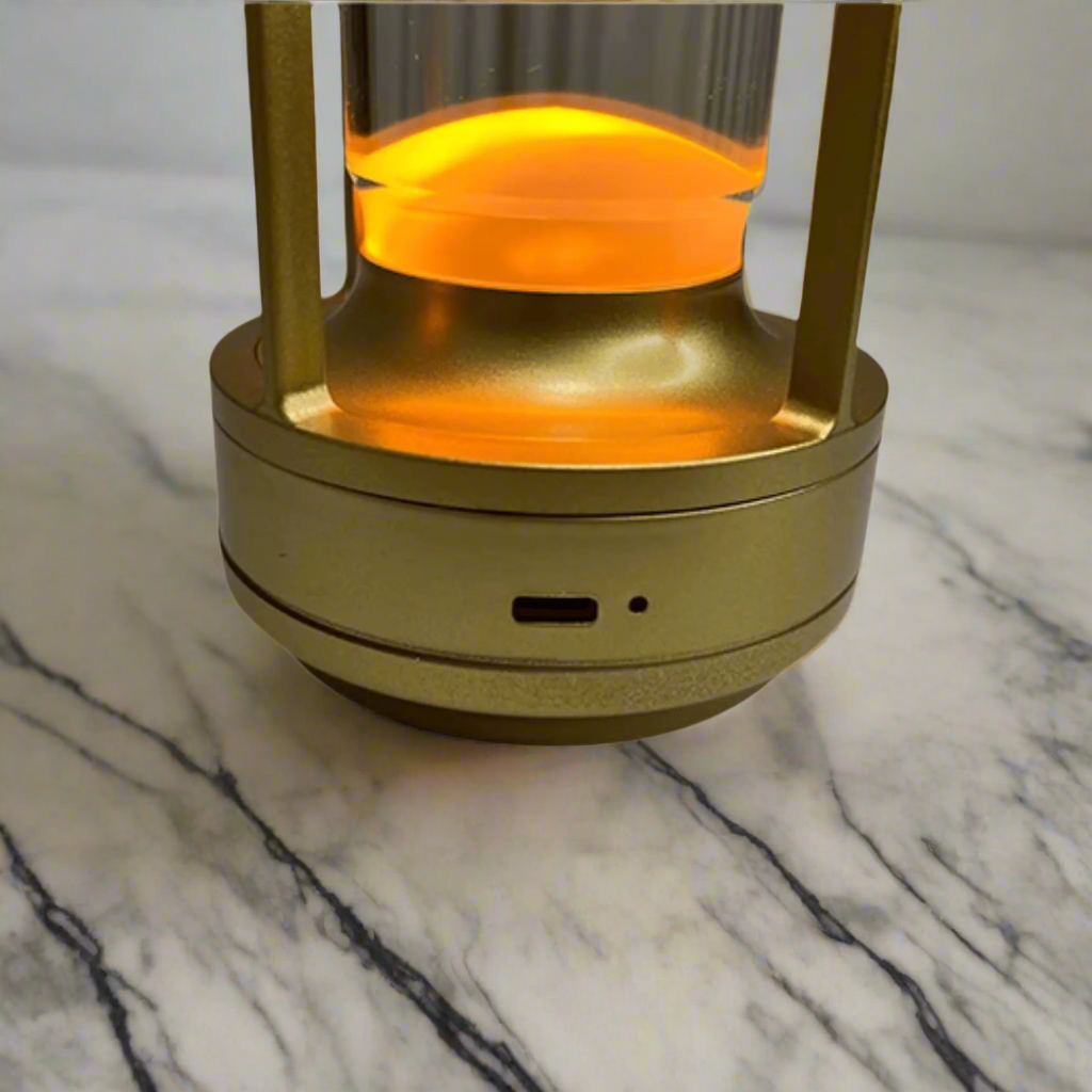 Gold-colored lantern with a glowing orange interior on a beige background