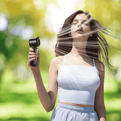 Woman using a hair dryer outdoors with a blurred green background