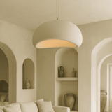 Beige pendant light hanging in a room with arched walls and shelves.