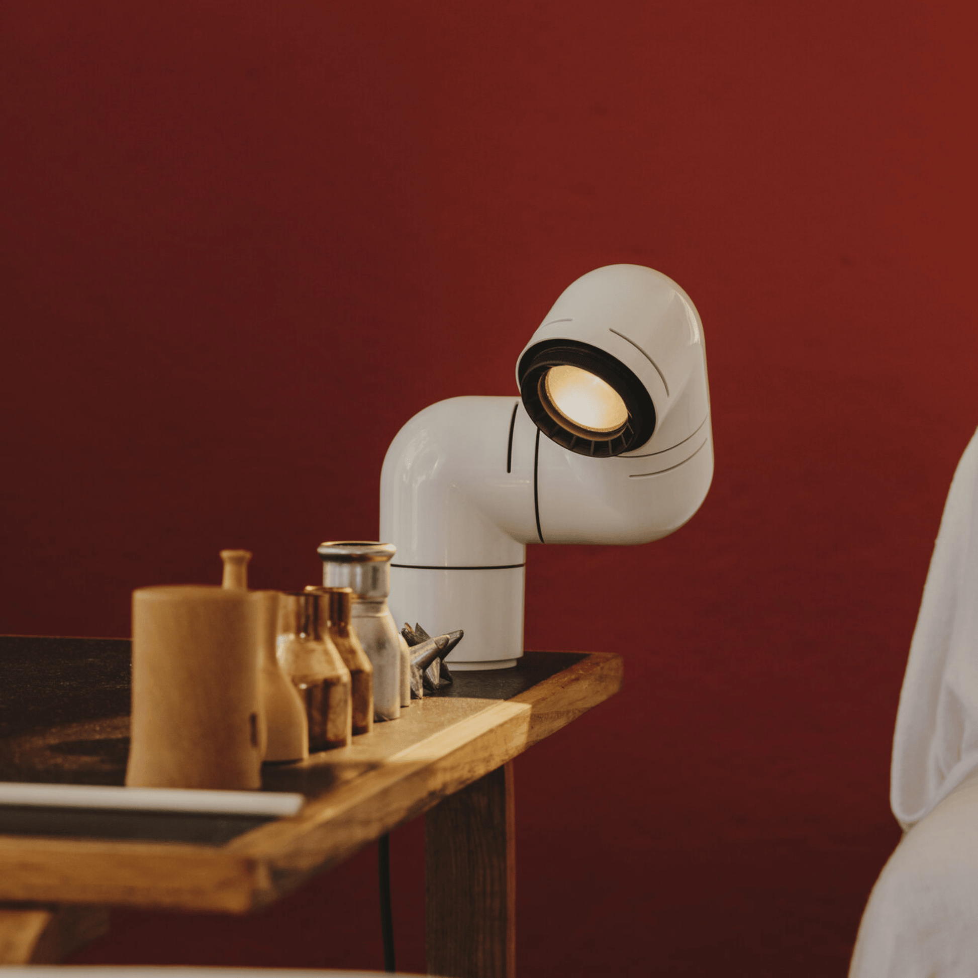Modern white lamp on a wooden surface with a red wall background