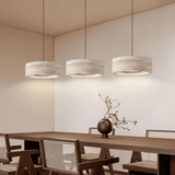 Three pendant lights hanging above a wooden dining table with chairs in a modern interior setting.