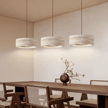 Three pendant lights hanging above a wooden dining table with chairs in a modern interior setting.