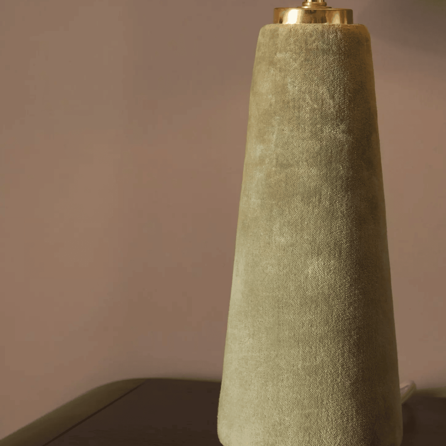 Textured green lamp with gold base against a neutral background
