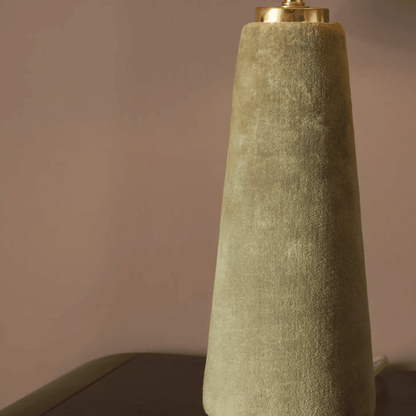 Textured green lamp with gold base against a neutral background