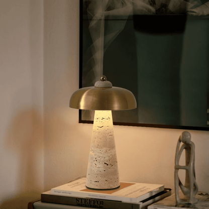 Table lamp with a textured base and gold shade on a stack of books, with a blurred background.