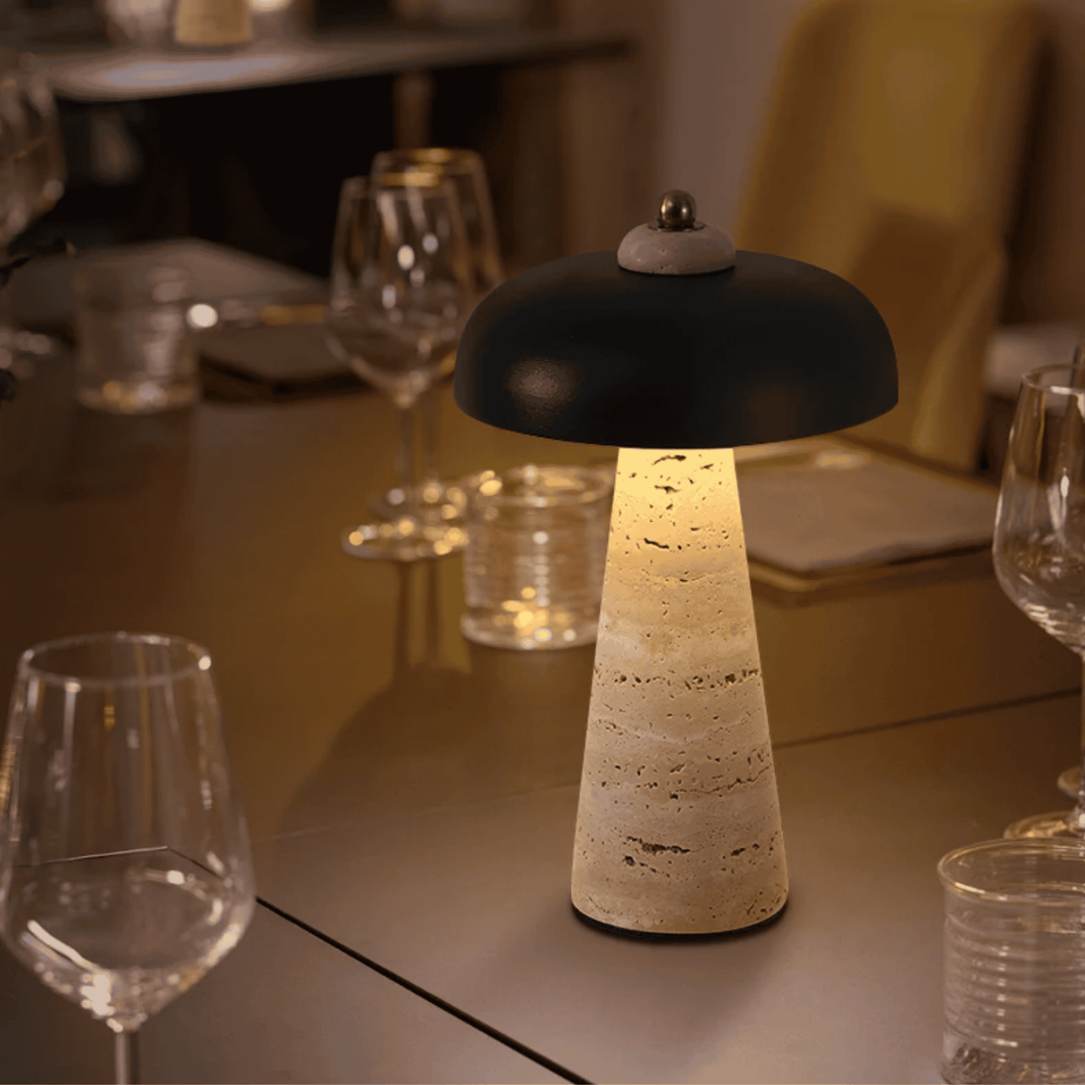 Decorative table lamp on a dining table with wine glasses and cutlery in the background