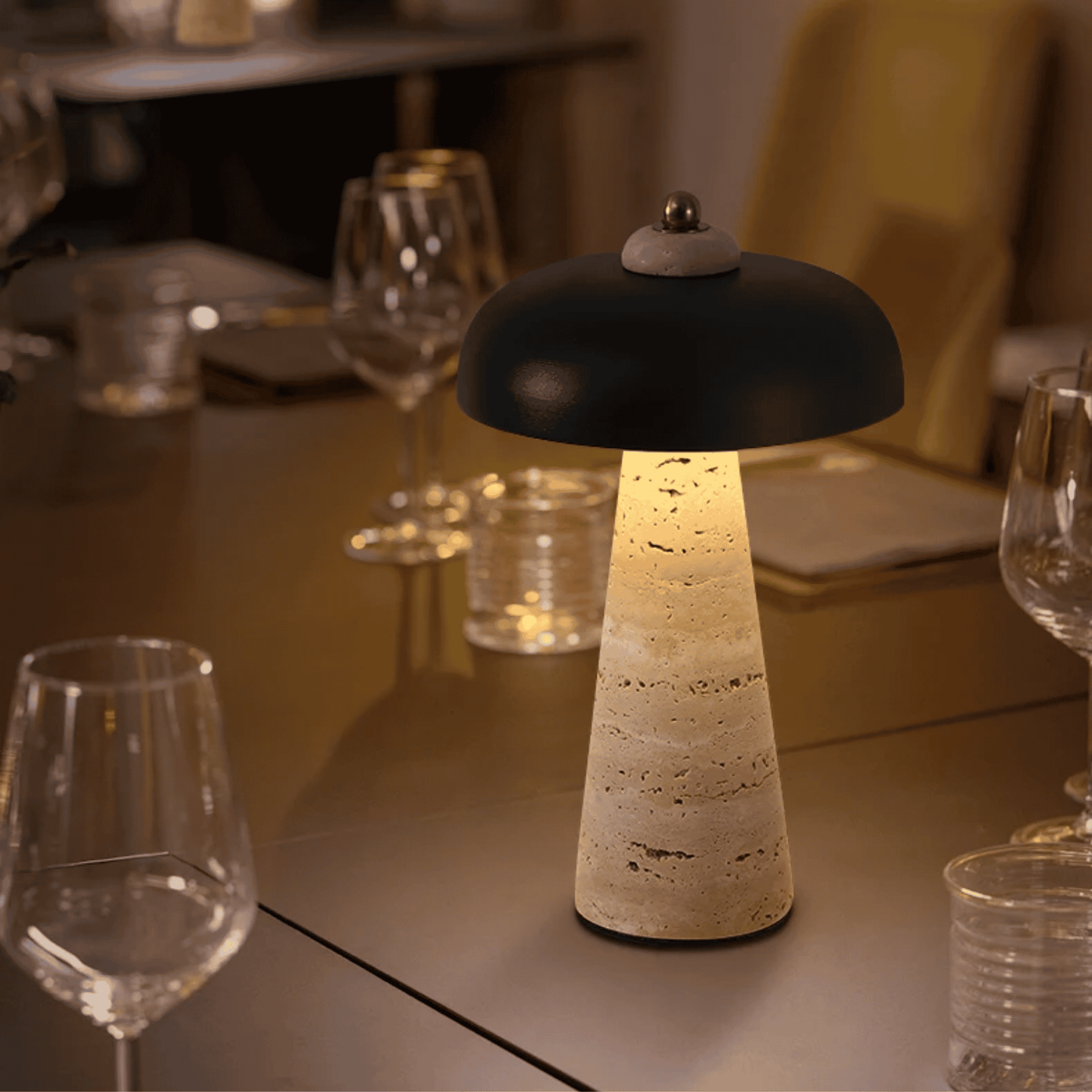 Decorative table lamp on a dining table with wine glasses and cutlery in the background